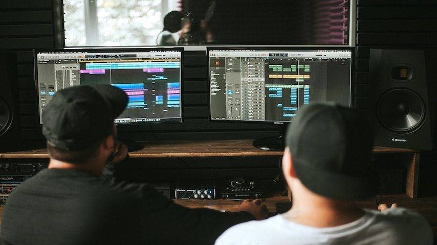 Image of two sound engineers editing audio. Used to illustrate the blog post The Ultimate Guide to Audio Editing for Voice-Over Recordings. Pexels license: https://www.pexels.com/photo/back-view-of-working-in-music-studio-11044765/