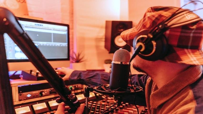Directing Voice Actors Remotely. Image of a man wearing a hat and headphones in a recording studio. Pexels licence: https://www.pexels.com/photo/orange-toned-image-of-a-man-wearing-a-hat-and-headphones-in-a-recording-studio-8133381/