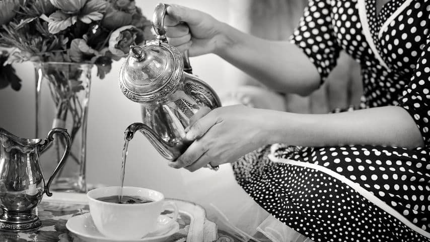 Leveraging the Posh Accent in Audiovisual Productions. Black and White Photo of a woman pouring tea into a teacup by JillWellington at Pixabay. Pixabay License. https://pixabay.com/photos/tea-party-tea-pour-pouring-tea-1001654/
