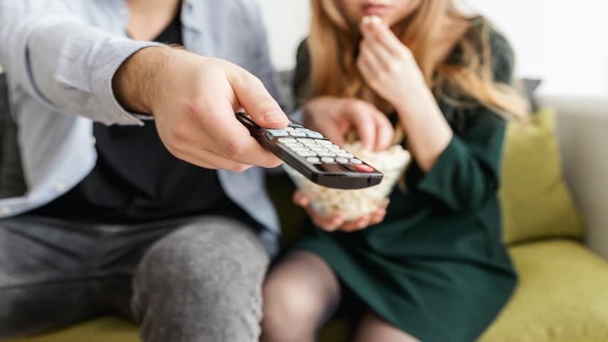TV Commercial Length. Image of couple watching tv and the man holding a remote control. This image is used to illustrate the article “TV Commercial Length for Effective Advertising”. Pexels license: https://www.pexels.com/photo/man-holding-remote-control-1040160/