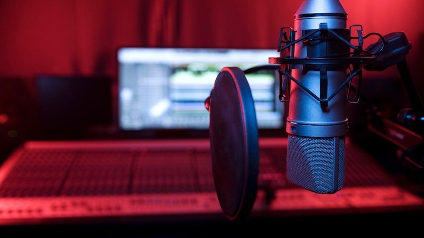 How to Dub Voice Over a Video. Photo of a close up microphone and pop filter in studio. This image is used to illustrate the article “How to Dub Voice Over a Video Like a Pro.” Freepik license: https://www.freepik.com/free-photo/close-up-microphone-pop-filter-studio_20931316.htm