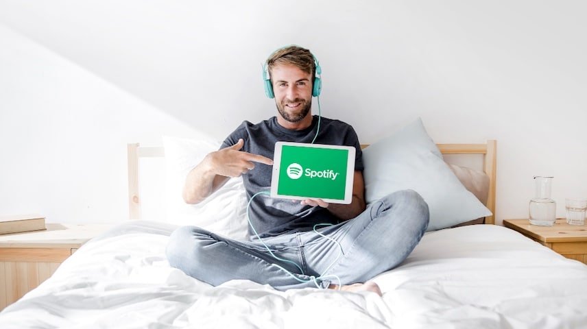 Spotify Advertising. Image of a young man holding tablet with Spotify app. This image is used to illustrate the article “Spotify Ads: Voice Over's Role in Engagement.” Freepik license: https://www.freepik.com/free-photo/young-man-holding-tablet-with-spotify-app_3421376.htm